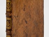 an old book with a brown cover sitting on top of a white surface