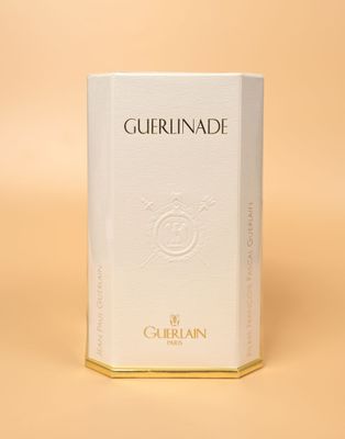 Parfum « Guerlaine by Guerlaine » présenté dans un coffret blanc sur fond beige