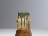 un vase marron et vert posé sur une table