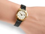 wrist shot of a woman ' s wrist with a gold and black watch