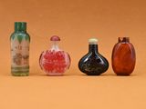 quatre bouteilles en verre de couleurs différentes posées les unes à côté des autres sur une surface marron