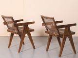 two wooden chairs sitting next to each other in a room