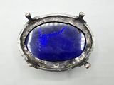 a close up of a metal object with a blue stone in it