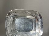 a silver plate sitting on a table next to a vase