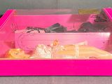 a pink box with a doll in it on a table