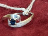 a silver ring with a blue stone on it on a red surface