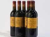 three bottles of red wine are lined up on a white surface