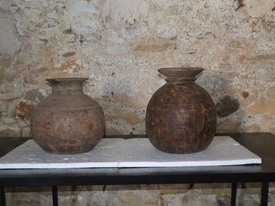 deux vases posés sur une table devant un mur de briques