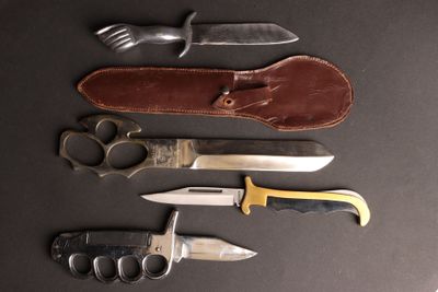 cinq types de couteaux différents posés sur une surface noire