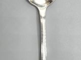 silver plated spoon with a curved handle on a gray surface