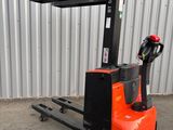 un chariot élévateur orange et noir garé devant un immeuble
