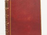 un vieux livre à la couverture rouge posé sur une surface blanche