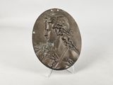 an image of a bronze medallion of a woman with braid hair