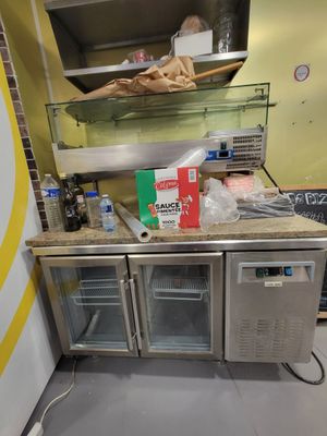 une cuisine équipée d'un réfrigérateur et d'un plan de travail sur lequel sont disposés de nombreux aliments