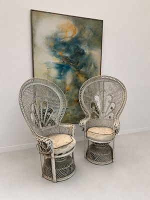 deux chaises en osier blanc devant un tableau, dans une pièce blanche