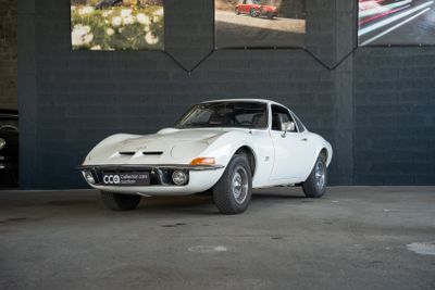 une voiture blanche garée dans un garage, avec des photos accrochées au mur derrière elle