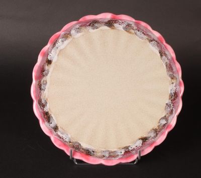 une pâte à tarte dans un moule à tarte rose posé sur une table noire