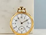 a gold pocket watch sitting on a marble block