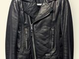 the leather jacket is hanging on a hanger on the wall