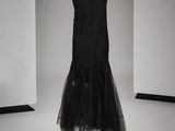 une robe noire posée sur un présentoir à mannequin dans une pièce