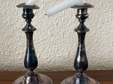 pair of silver candlesticks on a wooden table with a white wall in the background