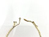 a close up of a necklace with pearls on a white background