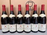 six bouteilles de vin rouge sont posées devant un carton