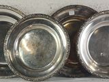 four silver plates are stacked on top of each other on a shelf