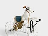 un cheval en peluche faisant du vélo sur une surface blanche