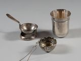 a silver cup with a spoon and a tea strainer