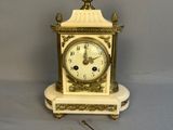 une petite horloge blanche ornée d'un motif doré