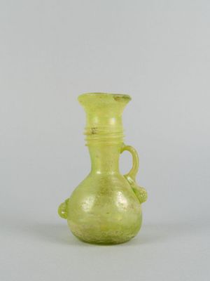 un vase en verre vert muni d'une anse, posé sur une table