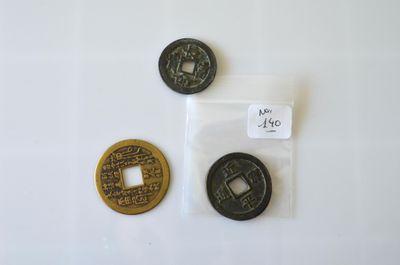 deux pièces chinoises et une pièce chinoise sont posées sur une surface blanche