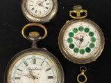trois montres de poche différentes posées sur une surface noire