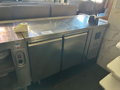 plan de travail en acier inoxydable dans une cuisine professionnelle, équipée d'un évier et d'un lave-vaisselle