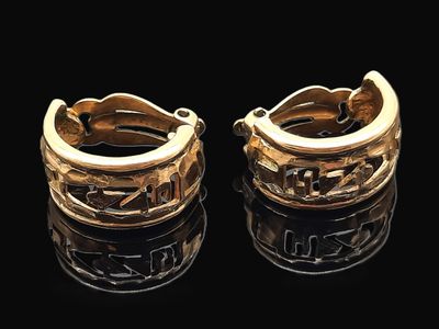 deux boucles d'oreilles en anneau dorées sur une surface noire, avec des reflets