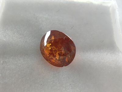 a close up of an orange diamond on a white surface