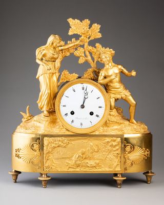 une image représentant une horloge en or surmontée de personnages