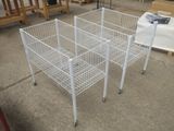 une cage métallique blanche posée au sol, munie de roulettes