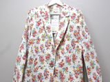 une veste blanche à motifs floraux suspendue à un cintre accroché au mur
