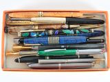 de nombreux stylos de toutes sortes dans une boîte posée sur la table