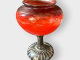 un vase rouge posé sur un socle en métal
