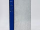 a silver book with a blue cover sitting on top of a white surface