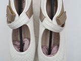 pair of white shoes with brown straps on top of a white box