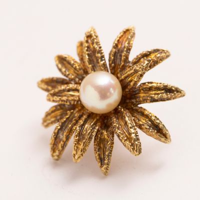 gros plan d'une bague en or avec une perle au centre