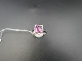 un gros plan d'une bague sertie d'un diamant rose sur une surface noire