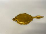gold plate with a spoon and spoon rest on a white surface