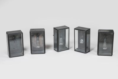 quatre lampes en verre noir sont alignées sur une surface blanche