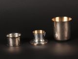 two silver cups and a silver cup on a black surface