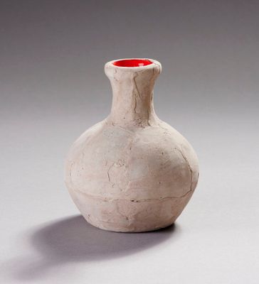 un vase blanc surmonté d'un couvercle rouge, posé sur une table